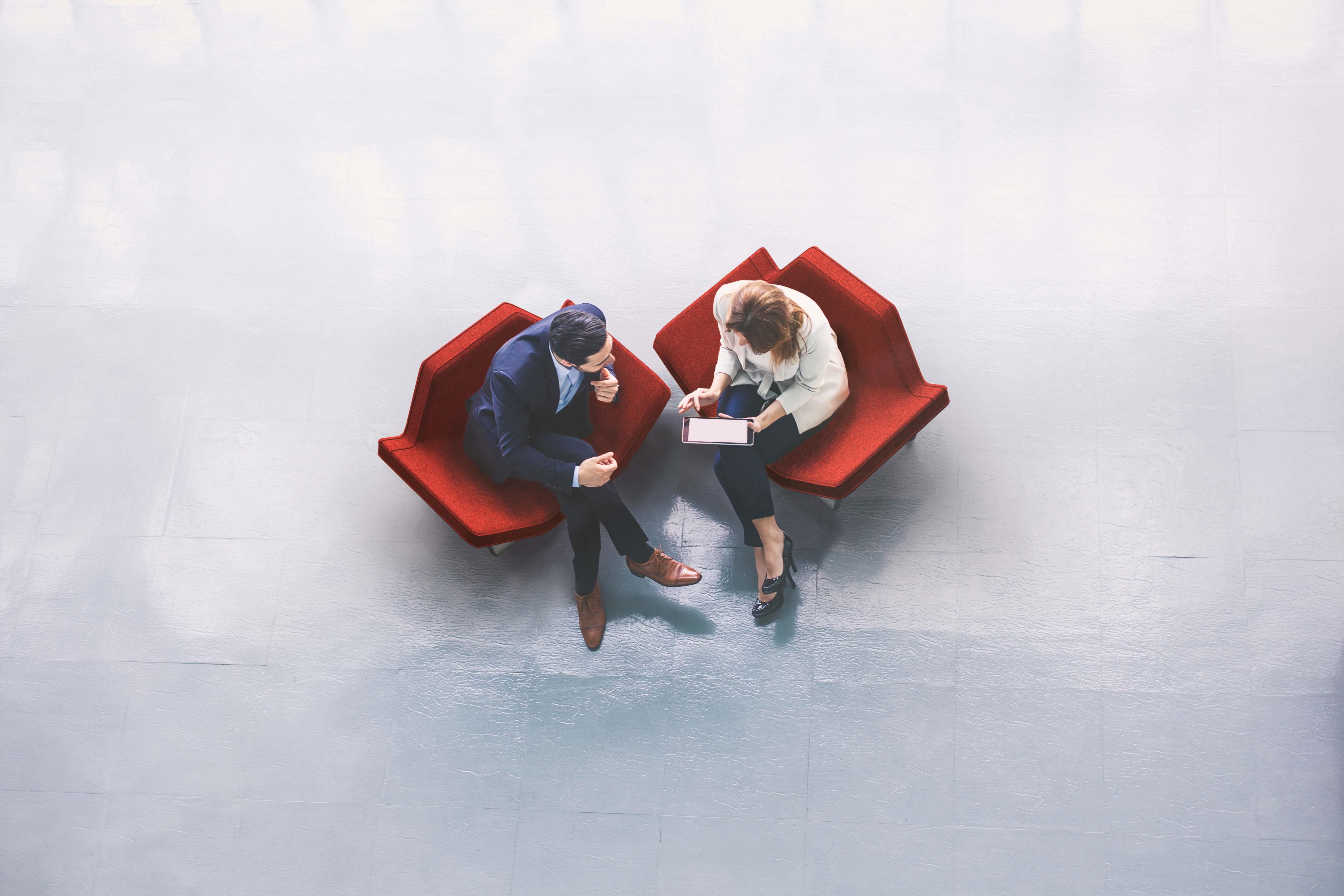Two professionals collaborating on red chairs