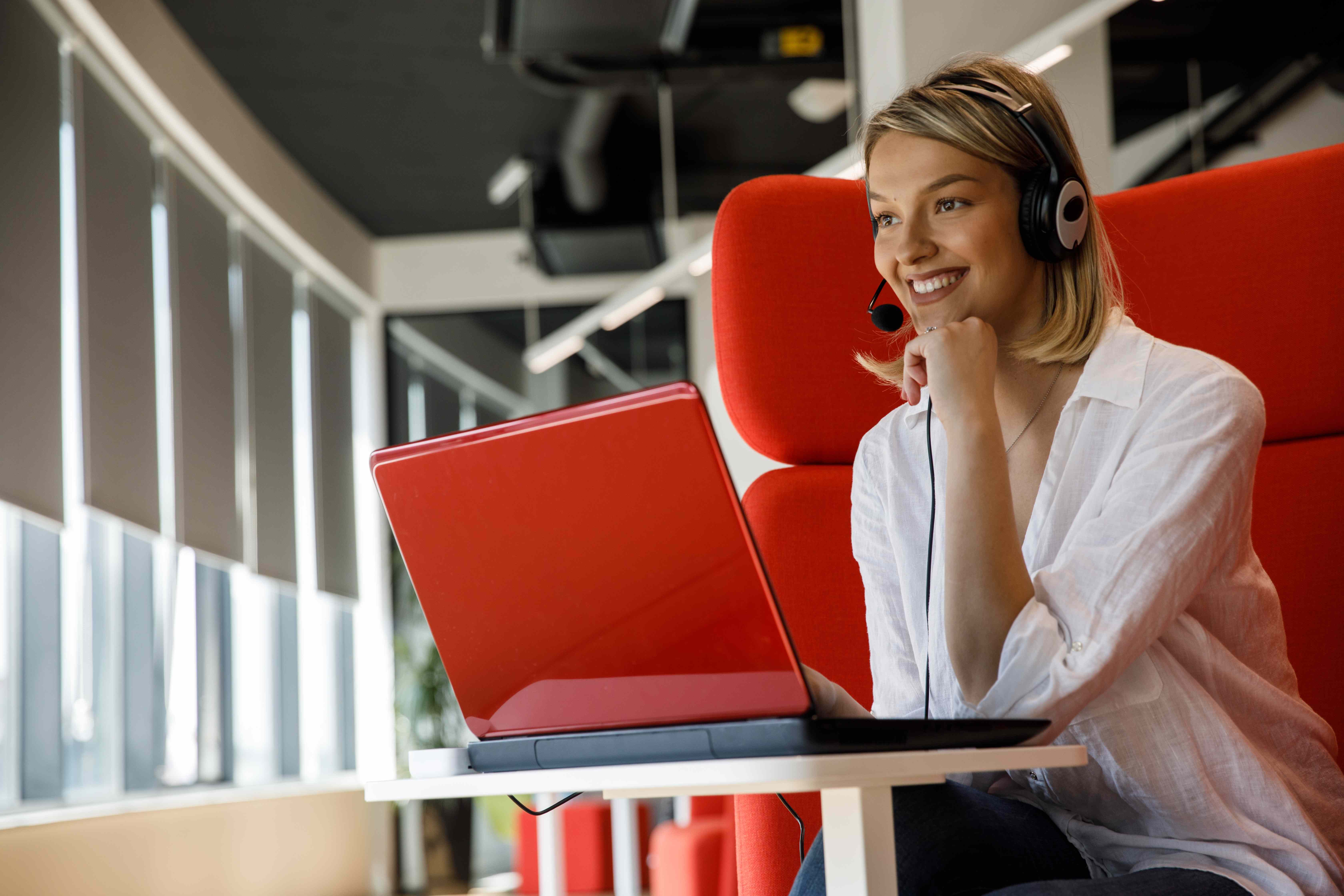 Professional working with headphones on red laptop